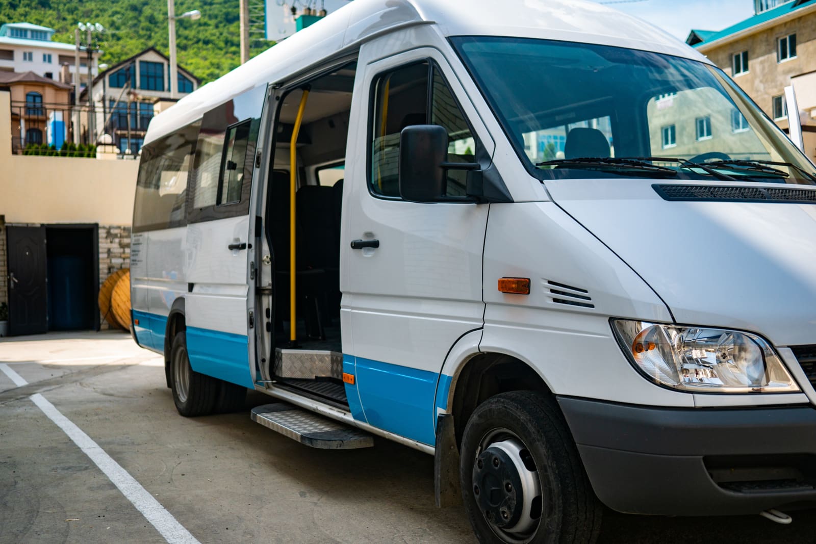 Tourist minibus is waiting with the door open in the parking lot.